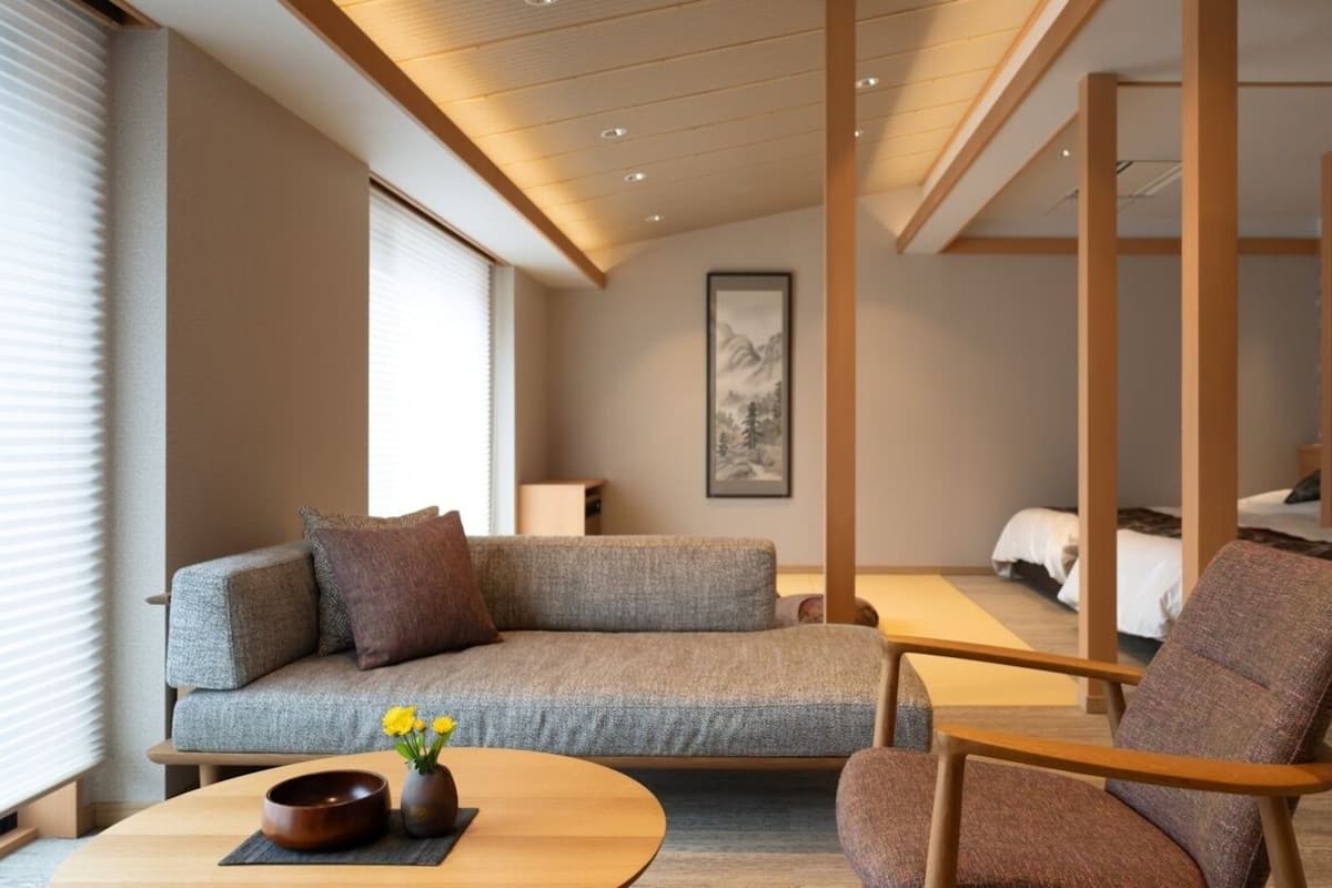 A modern hotel room with a sofa, chair, and a bed.