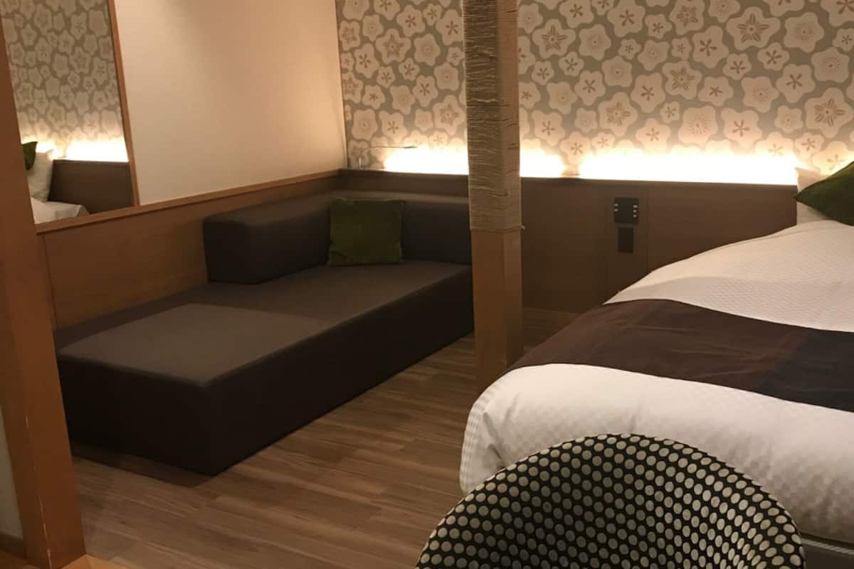 Un dormitorio con una cama, un sofá cama, una mesita de noche y una lámpara de pared.