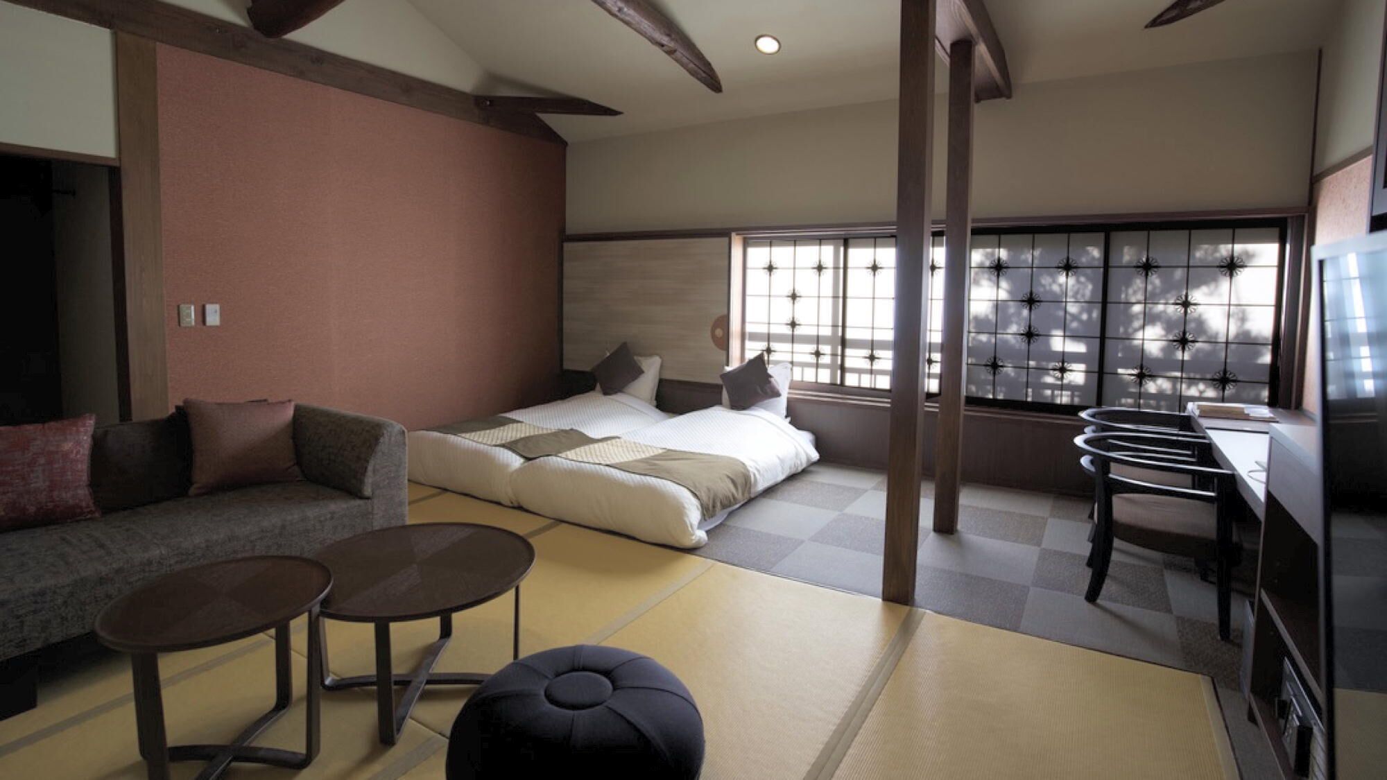 Una habitación de hotel moderna con cama, sofá, pequeñas mesas y suelo de tatami.