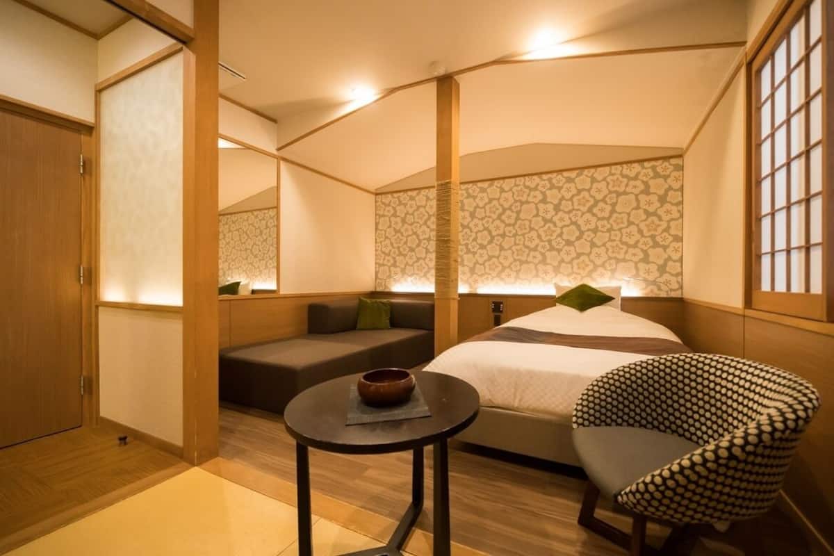A room with a bed, a sofa, a small table, and a chair.