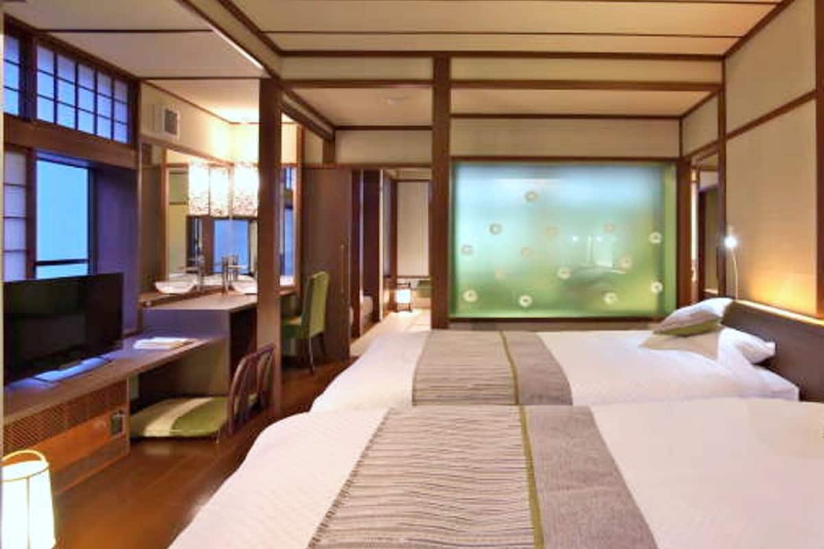 Una habitación de hotel con cama, escritorio, silla y televisor.