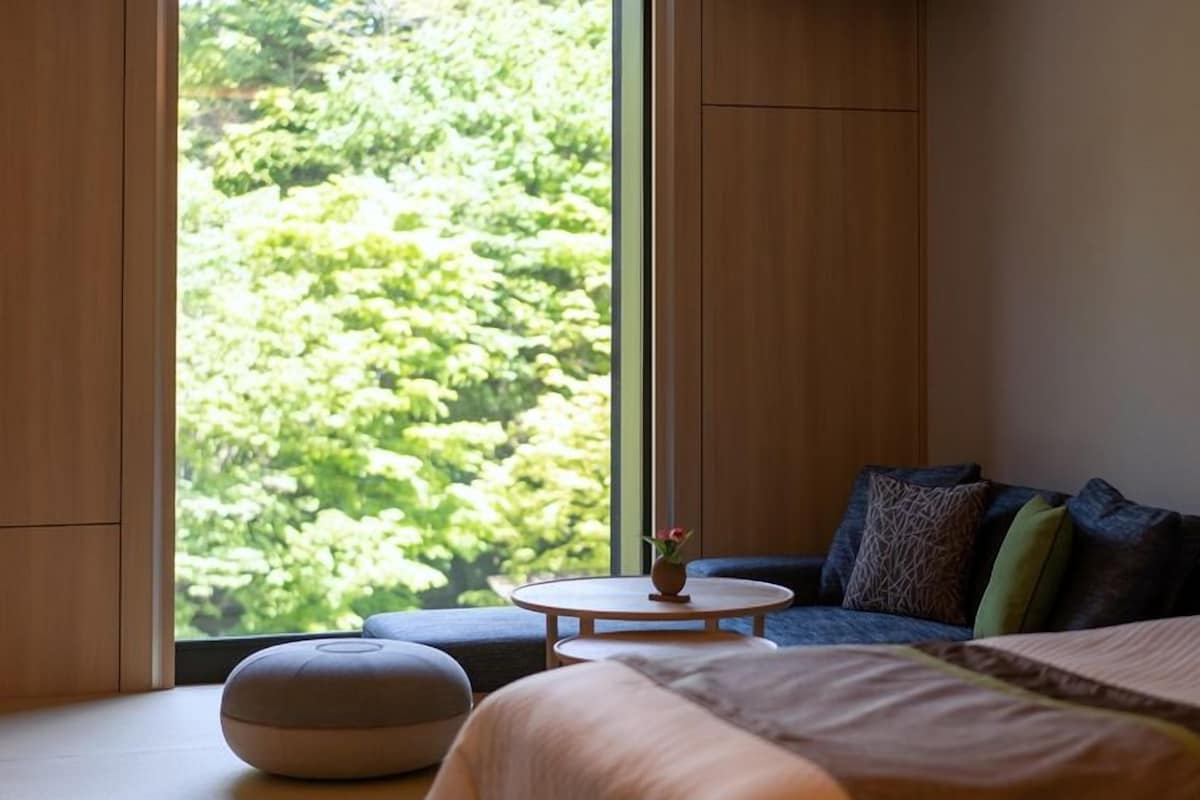 Une chambre avec une grande fenêtre, un lit, une table ronde et un canapé.