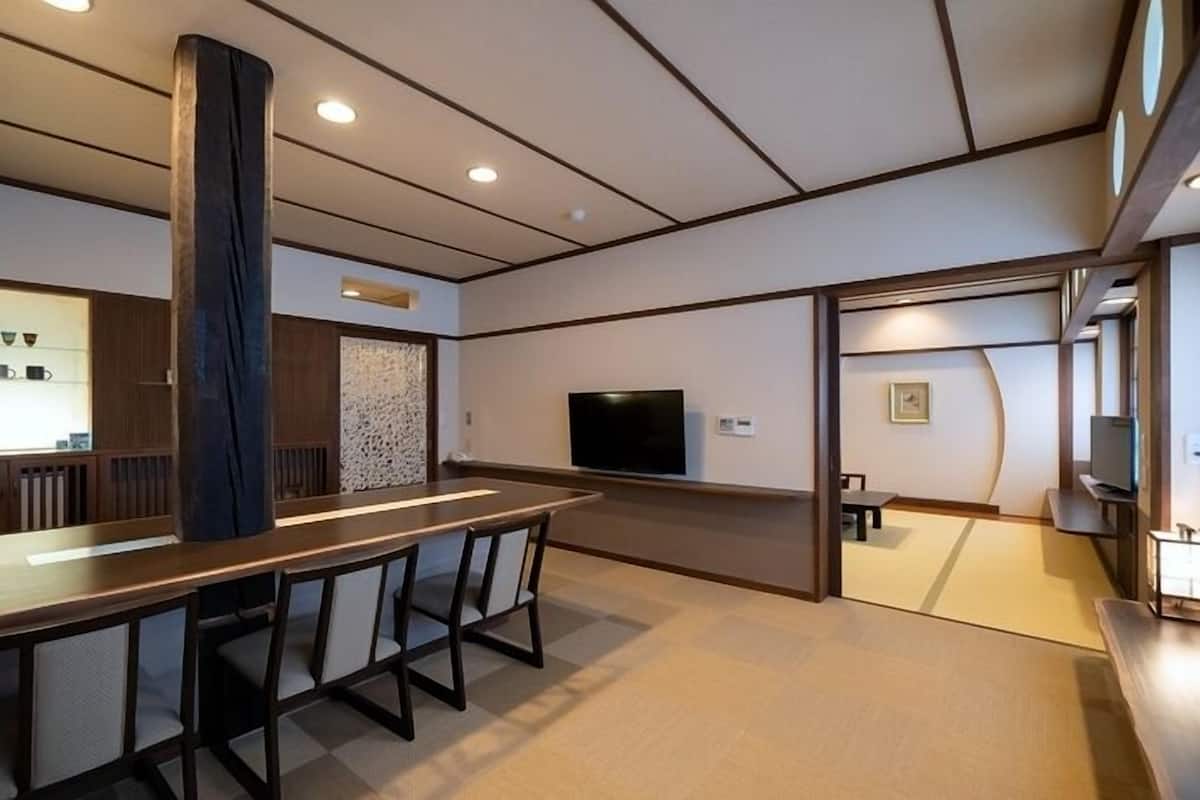 Una habitación de hotel moderna con una zona de bar, asientos, televisión y una pared de acento de piedra.