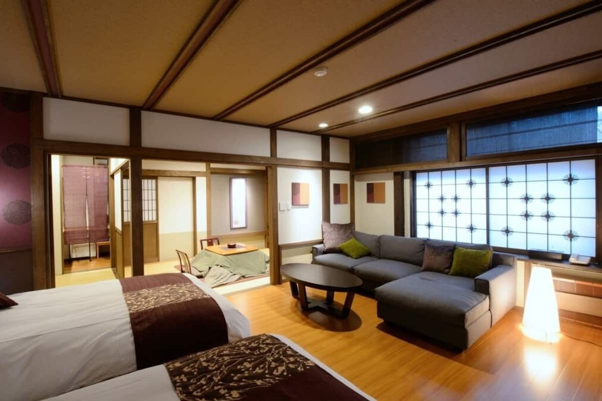 A hotel room with a bed, sofa, and a small dining table.