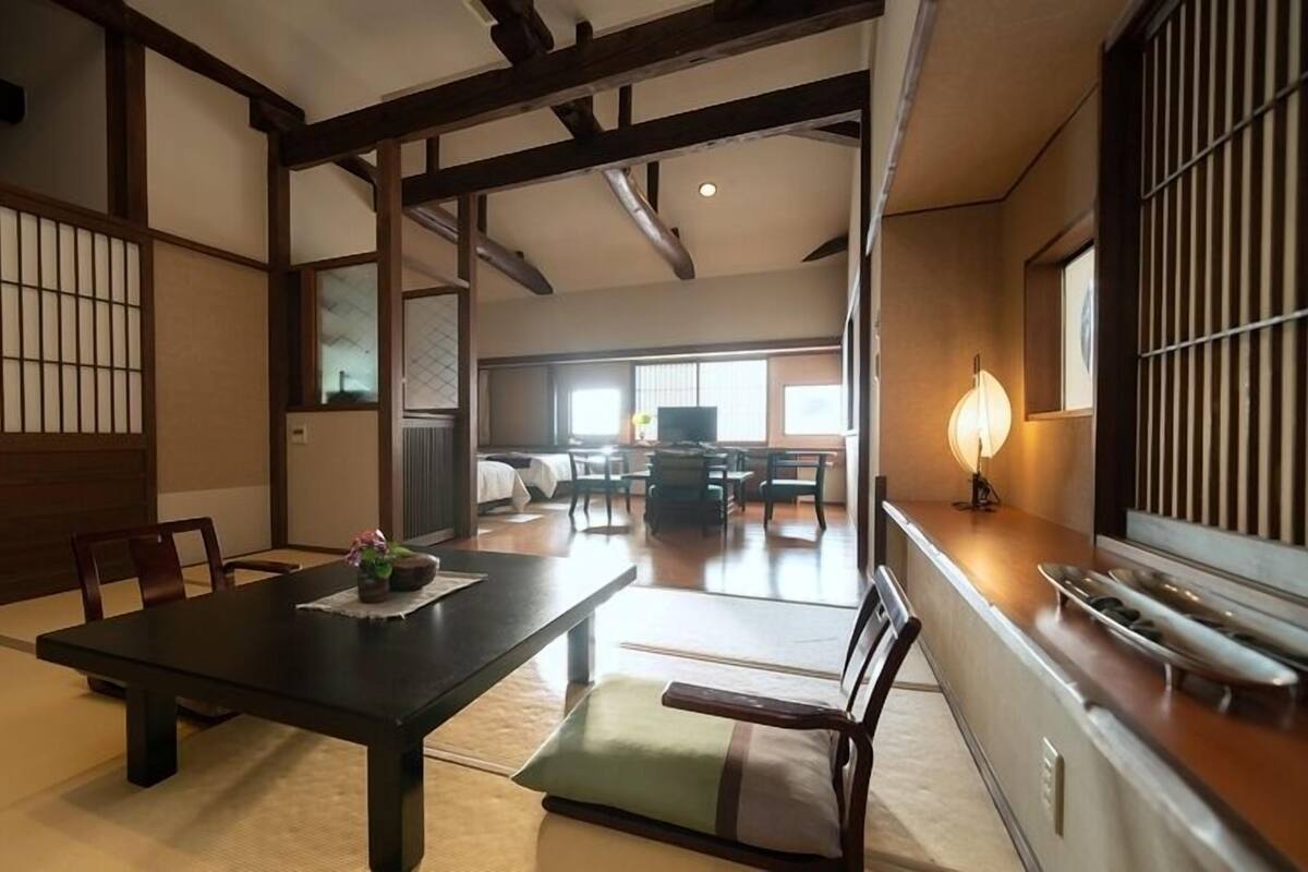 A traditional Japanese-style room with tatami flooring, a low table with a cushion, and sliding doors.