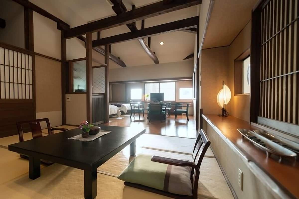 Una habitación tradicional japonesa con suelo de tatami, una mesa baja con cojín y puertas correderas.