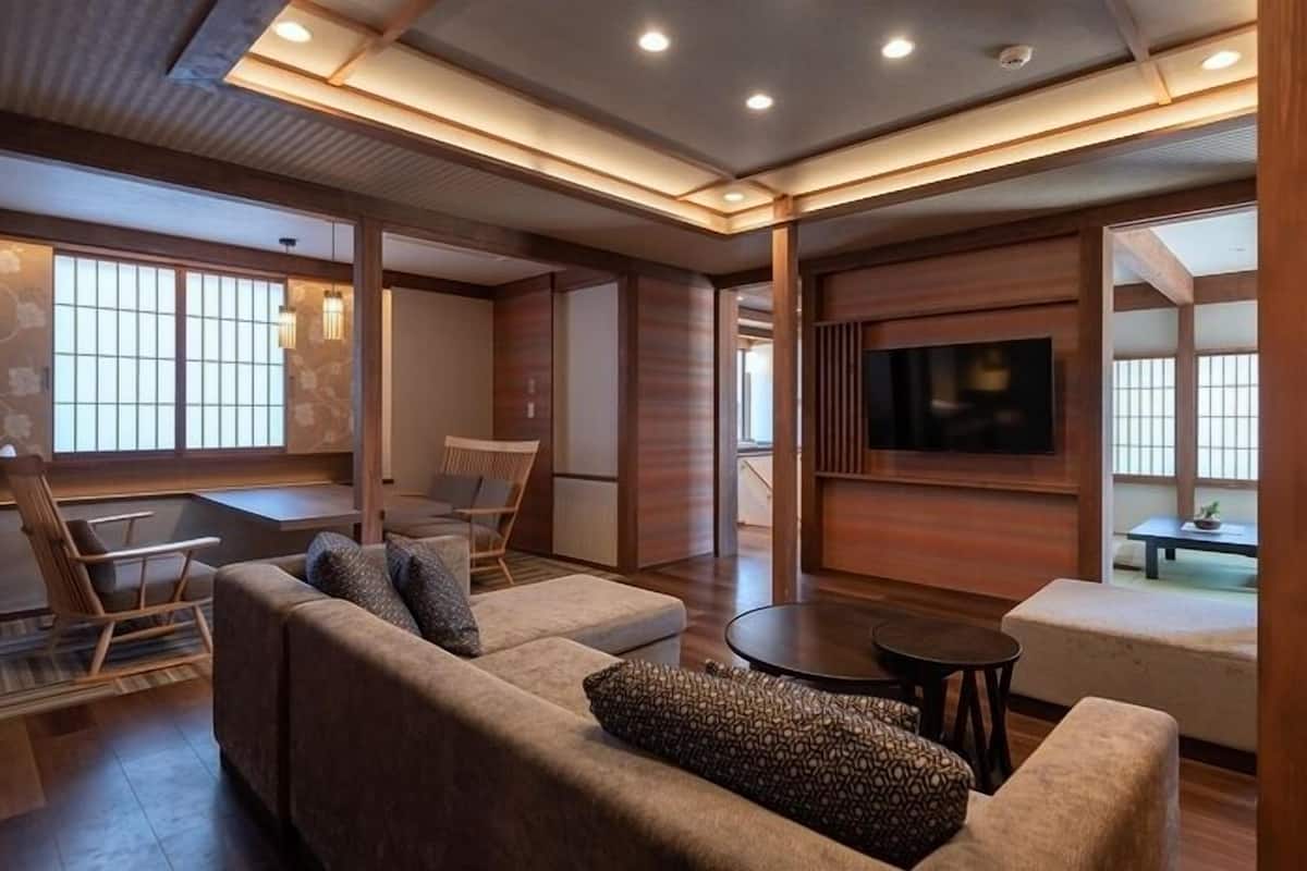 A modern living room with a sofa, chairs, a TV, and a wooden floor.