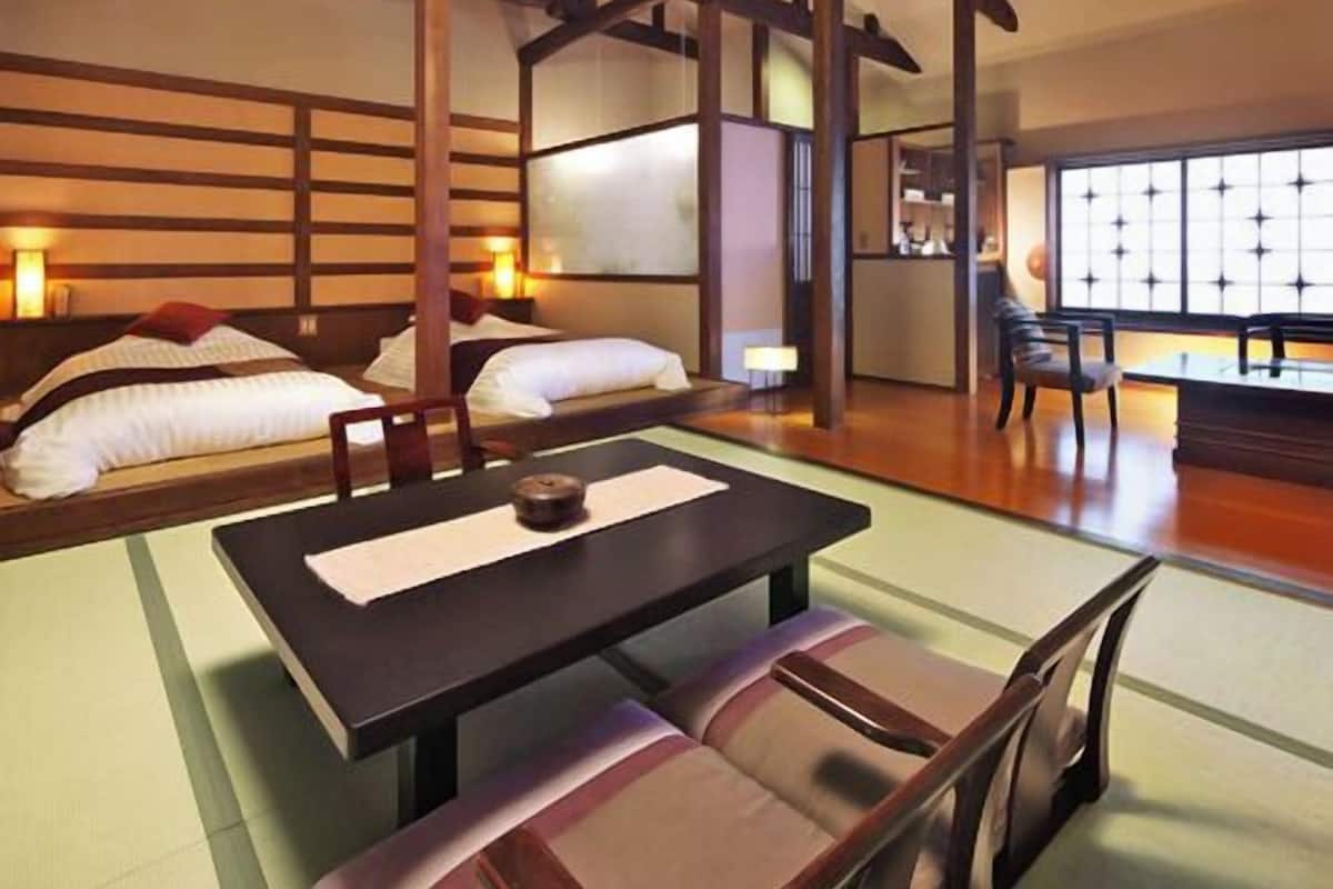 A traditional Japanese-style room with tatami flooring, a low table, and a futon bed.