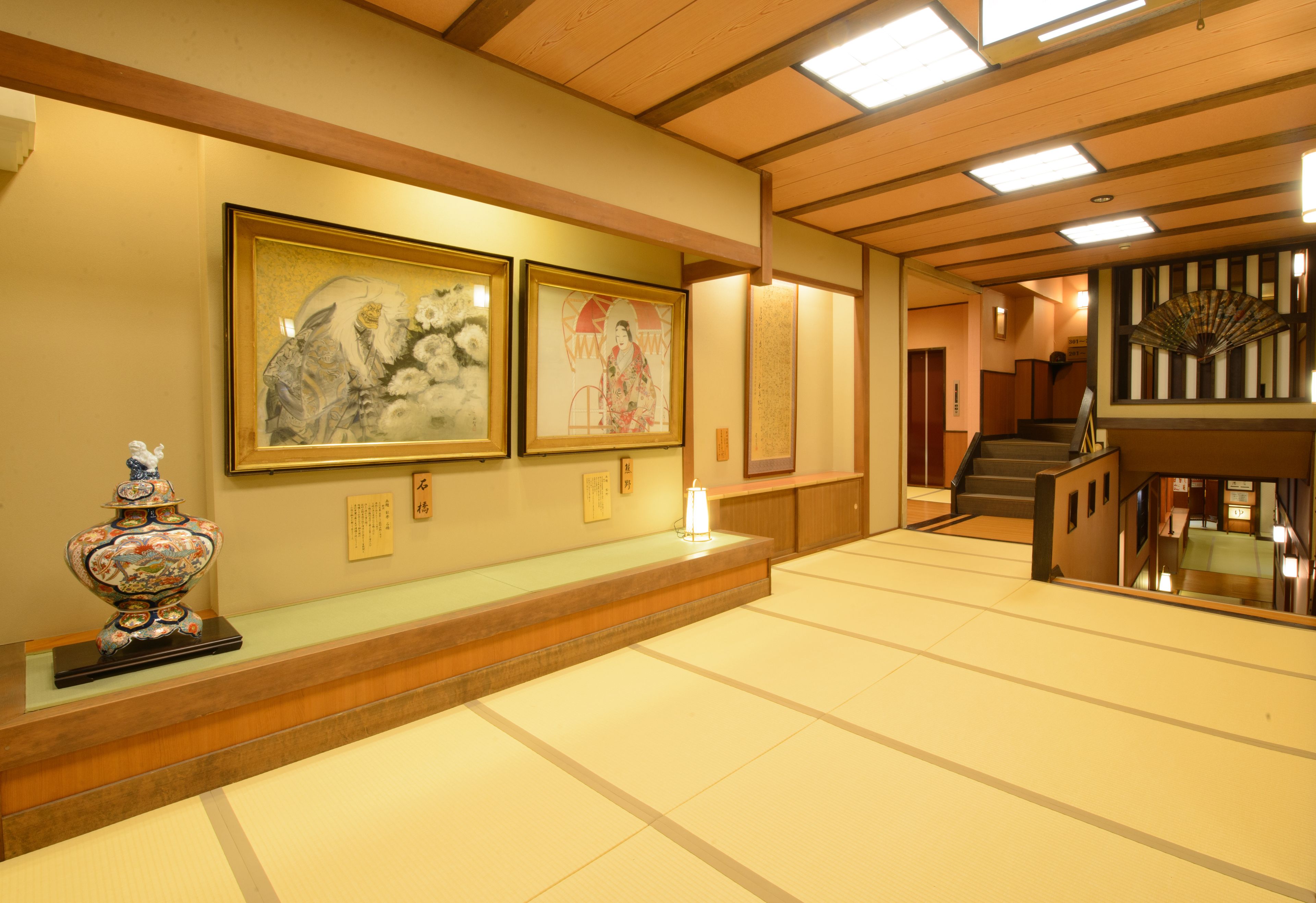 A traditional Japanese interior with tatami flooring, wooden beams, and artwork on the walls.