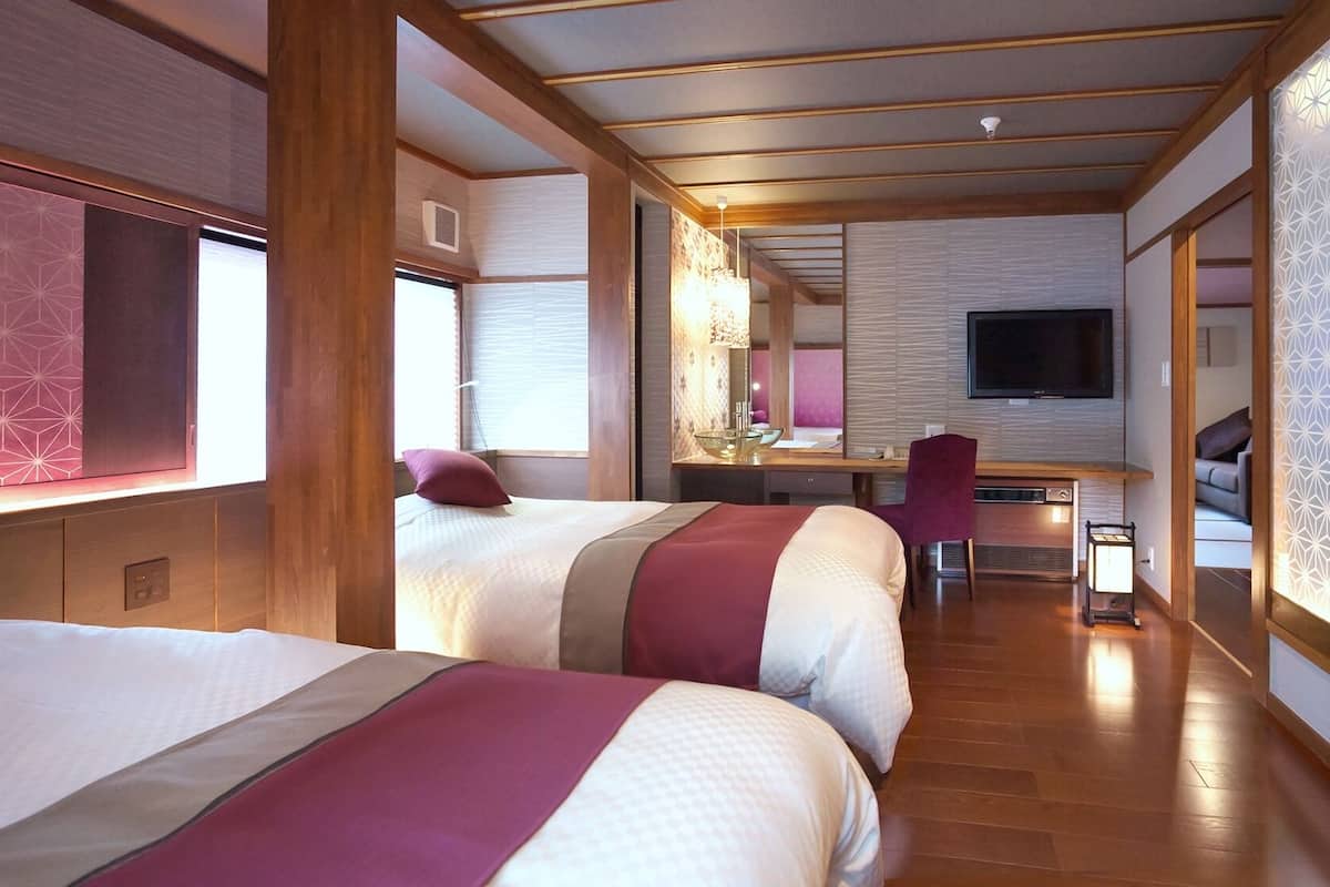 Habitación de hotel con dos camas, un escritorio, un televisor y un baño.
