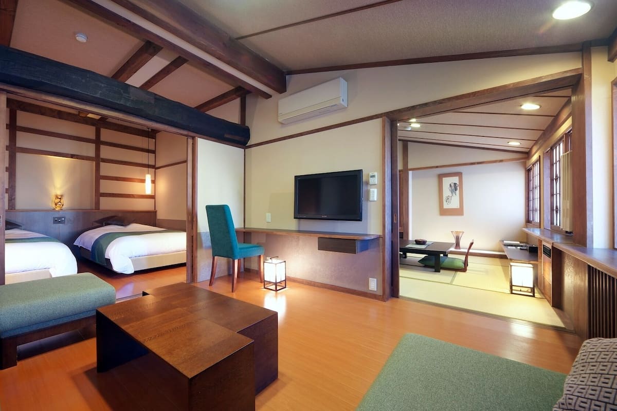 Una habitación de hotel con cama, sofá, televisión y zona de comedor.