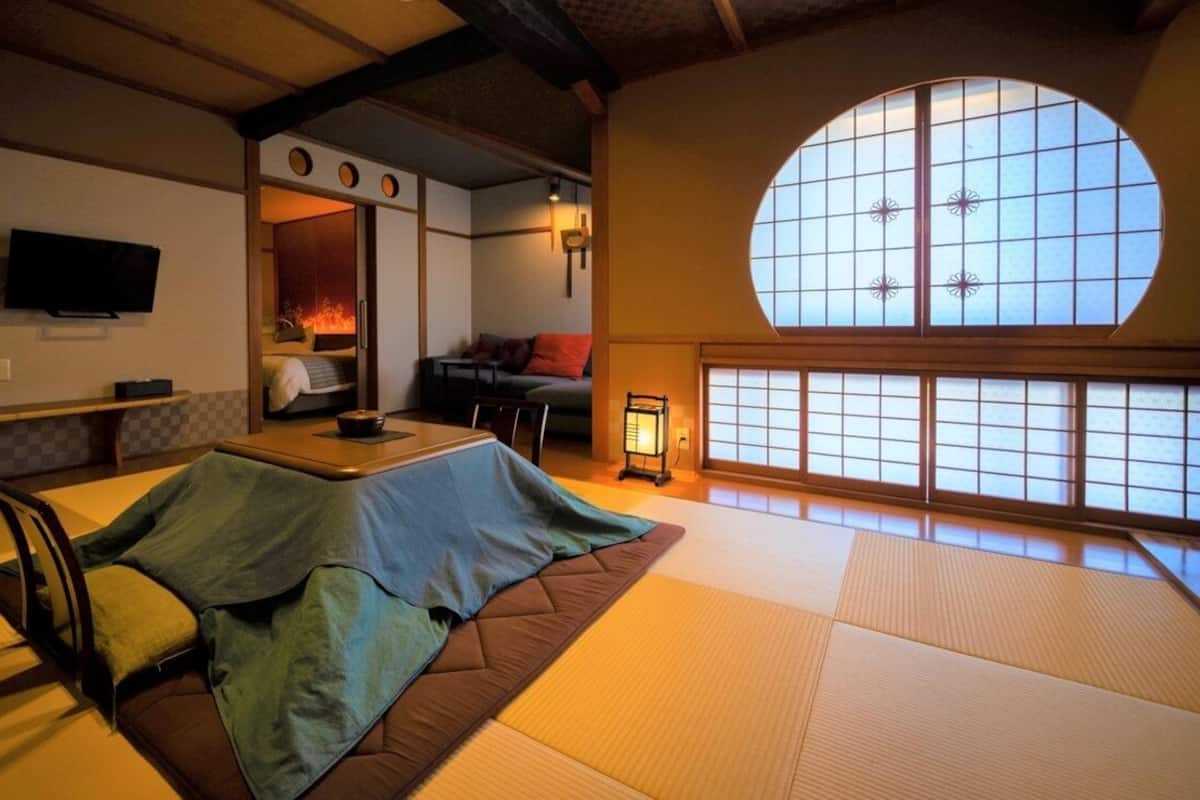 A tatami mat room with a futon bed, a television, and a large window with a decorative grid.