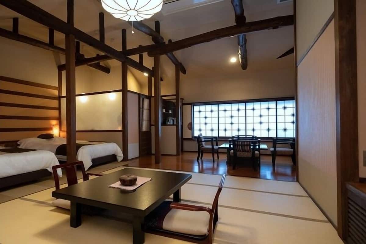 A traditional Japanese-style room with tatami flooring, a low table with cushions, and a sliding door leading to another room.