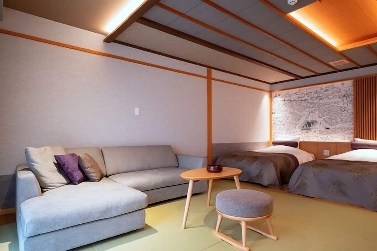A modern room with a sofa, a small round table, and a bed with a headboard.
