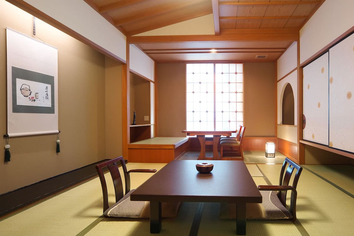 A traditional Japanese room with tatami flooring, a low table, and sliding doors.