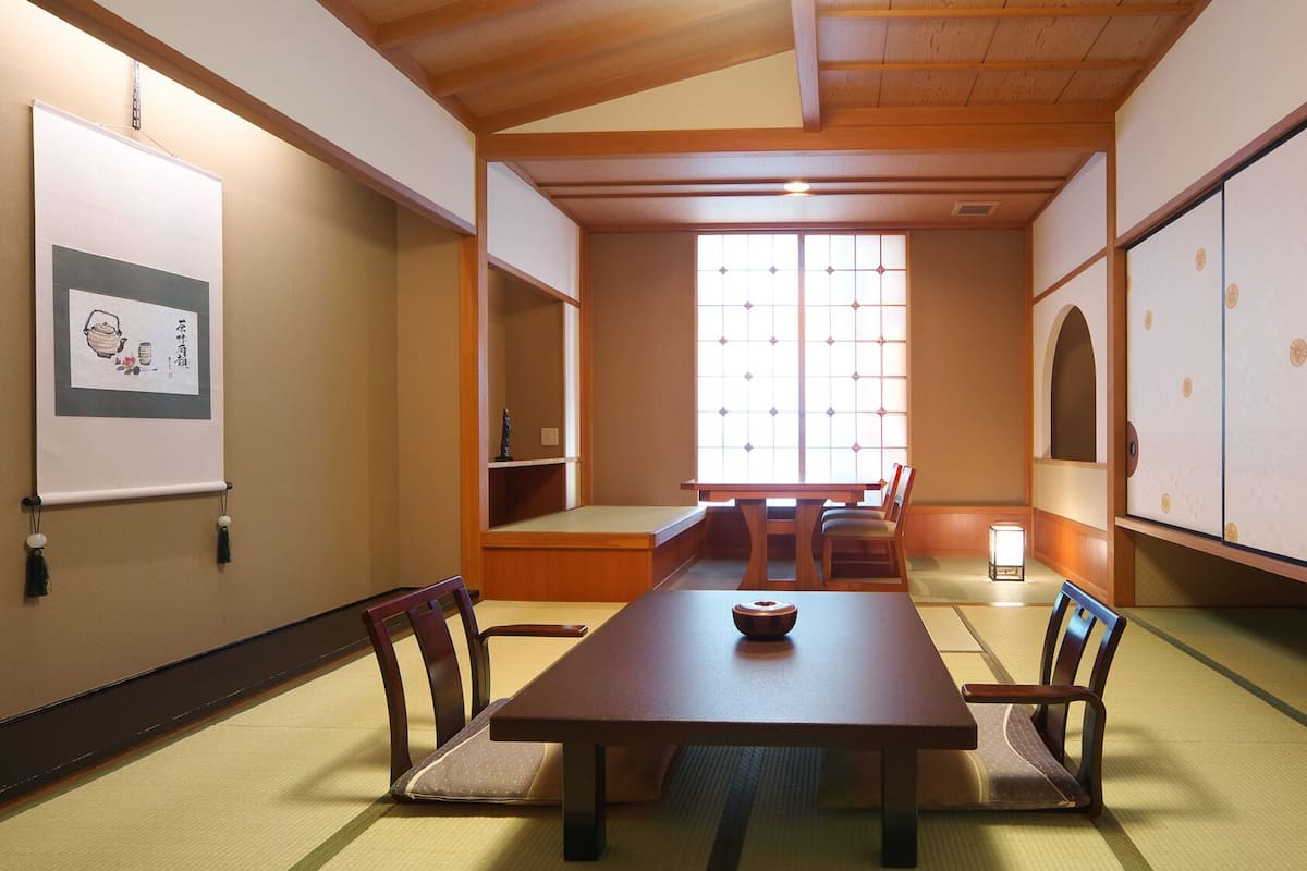 Una sala de reuniones tradicional japonesa con suelo de tatami, una mesa baja y puertas correderas.