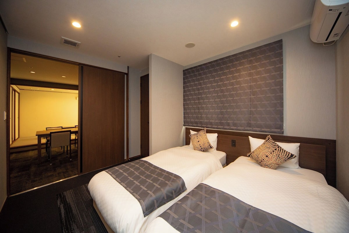 Une chambre d’hôtel avec deux lits, un coin repas et un appareil de climatisation.