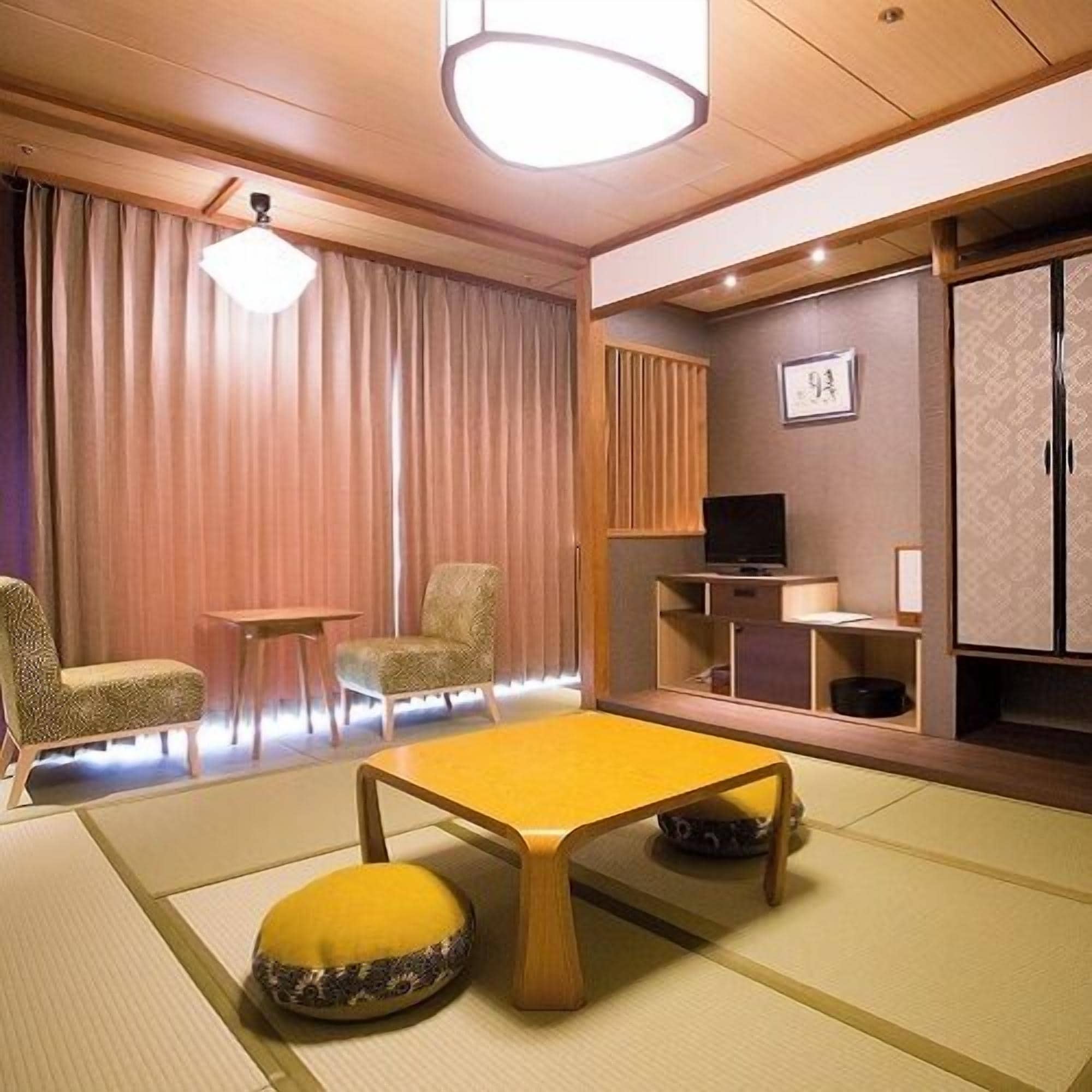 Une pièce de style japonais traditionnel, avec un sol recouvert de tatamis, une table basse, un téléviseur et un meuble.
