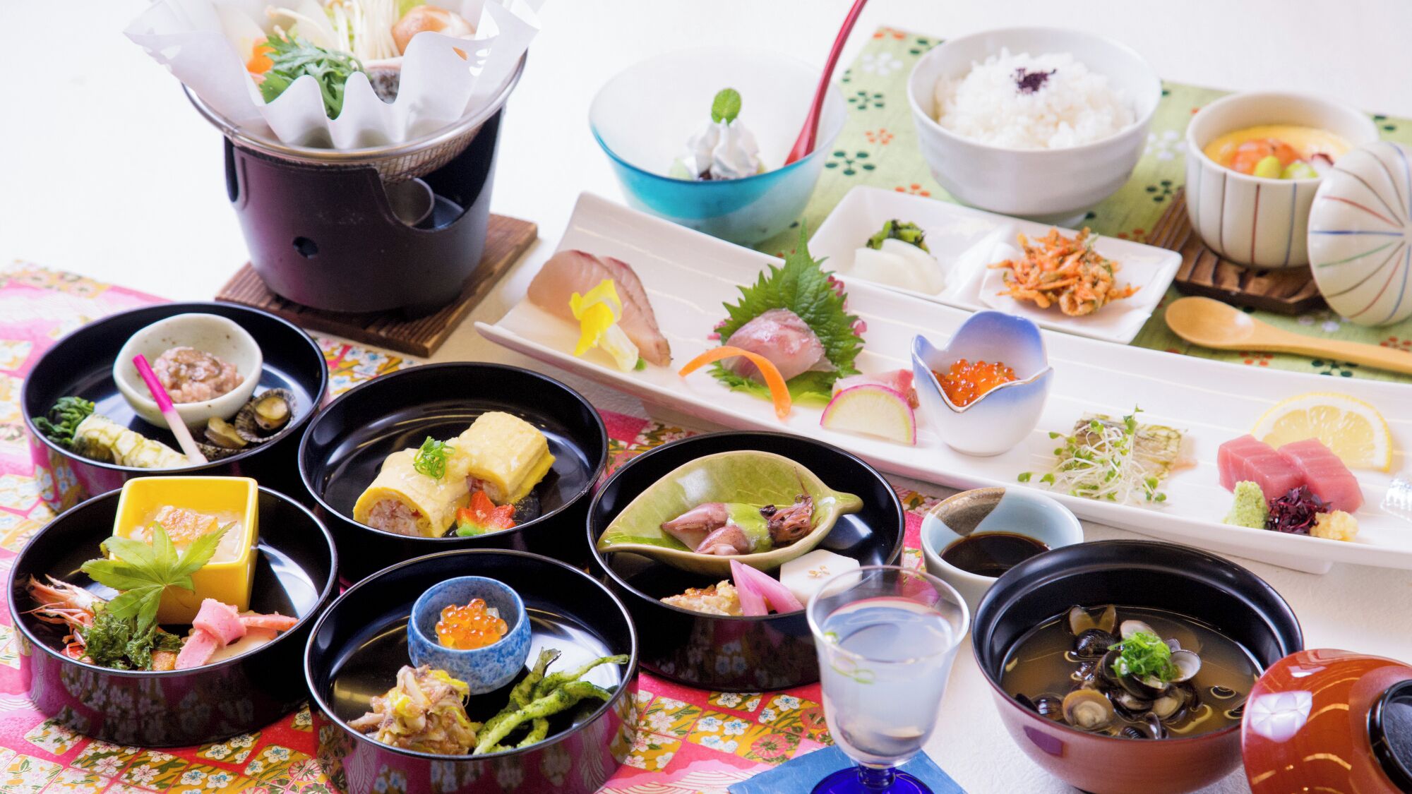 Diverse Japanse gerechten gerangschikt op een tafel met een tafelkleed met bloemenmotief.