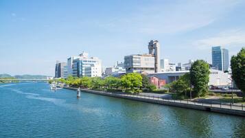 A waterfront cityscape with modern buildings, a river, and a bridge.