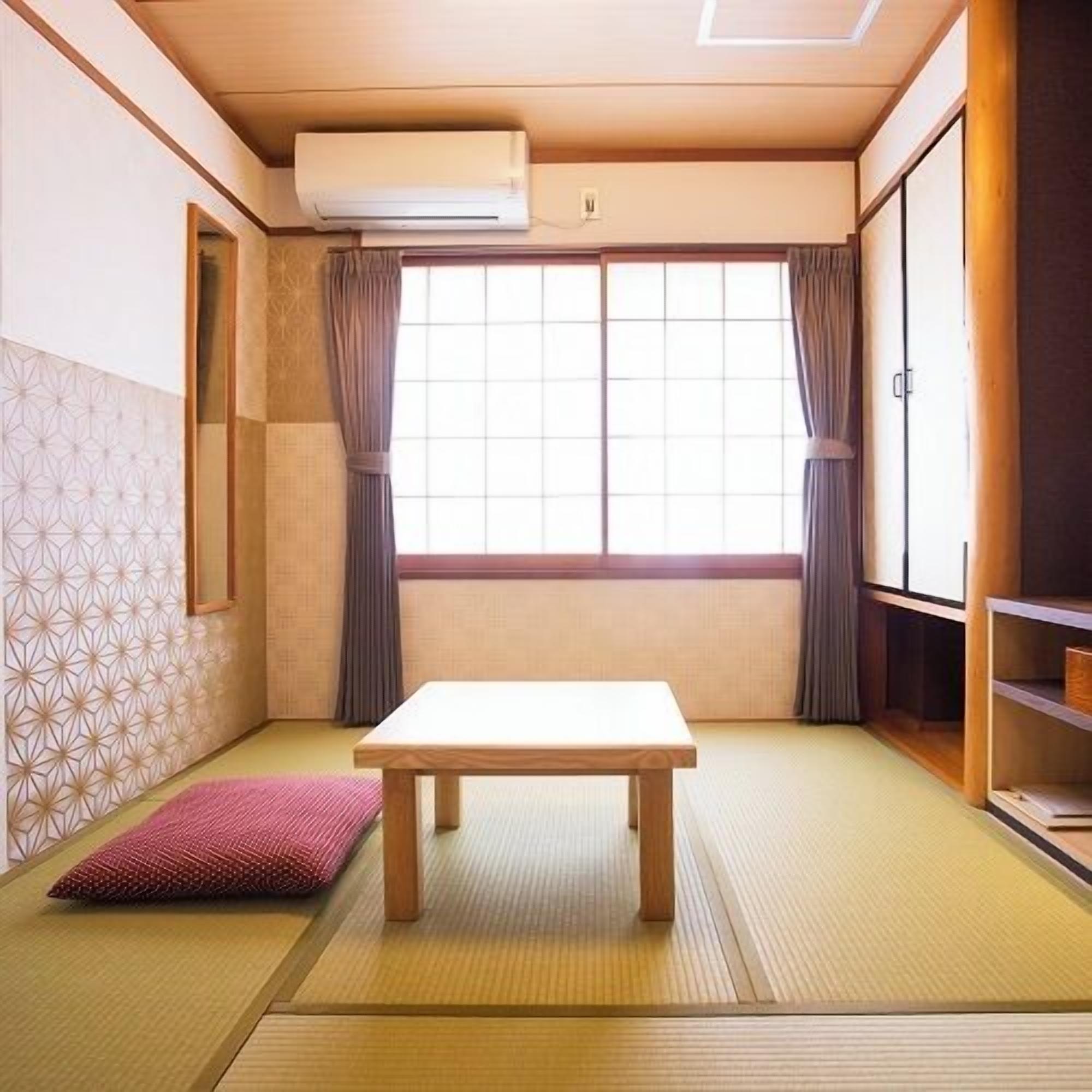 Une pièce de style japonais traditionnel, avec un sol recouvert de tatamis, une table basse et des portes coulissantes.