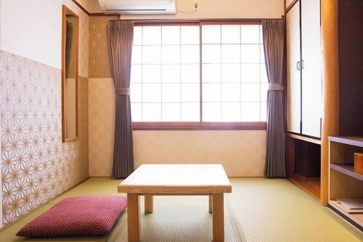 Una tradizionale stanza giapponese con pavimento in tatami, un tavolino basso e porte scorrevoli.