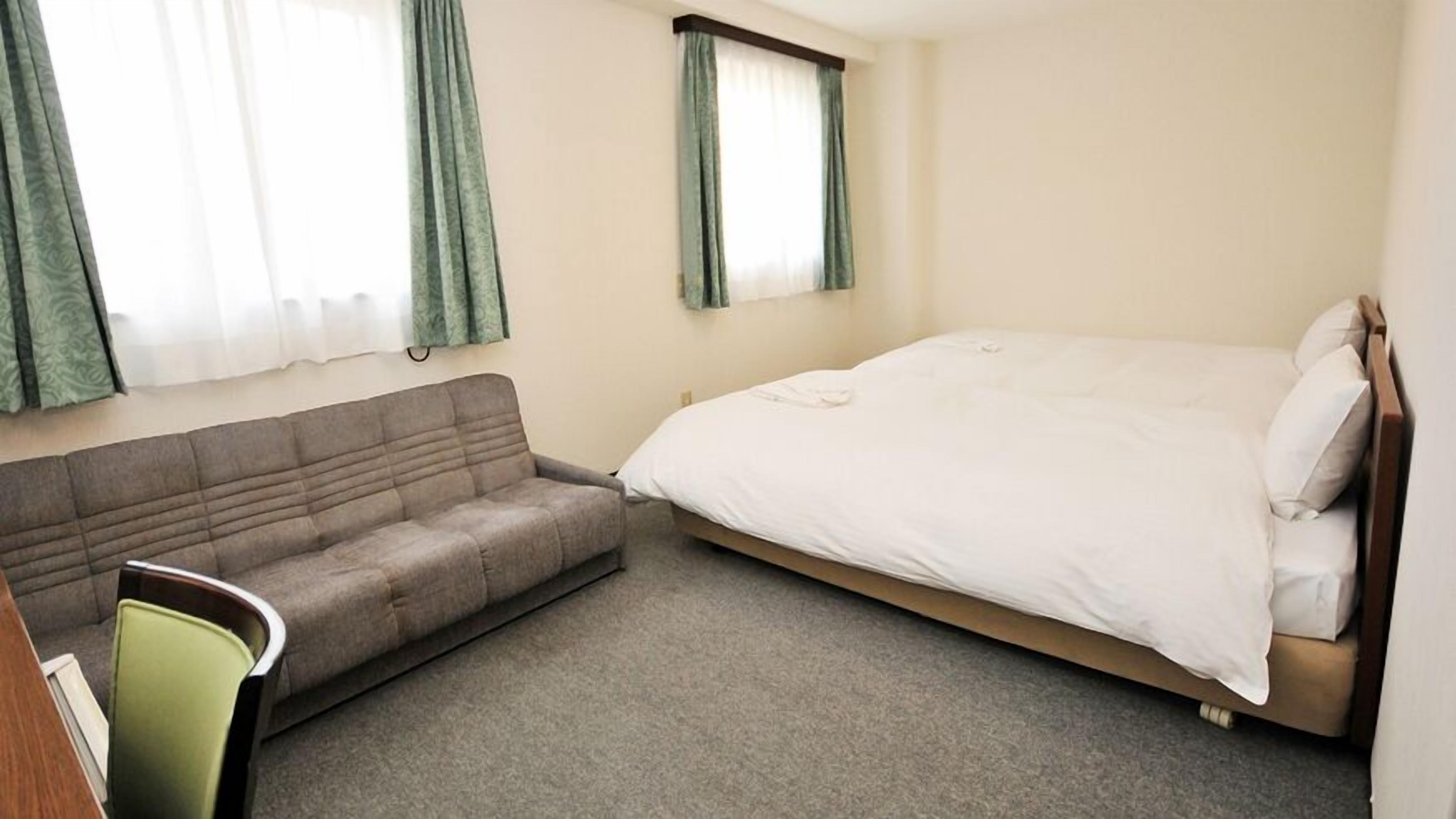 Una habitación con una cama, un sofá y una silla.