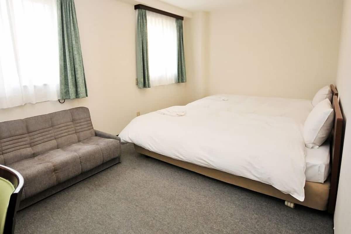 Una habitación con una cama, un sofá y una silla.
