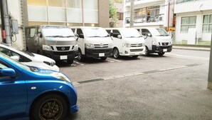 A parking area with several white vans and a blue car. - Hotel Green Line (Sendai)