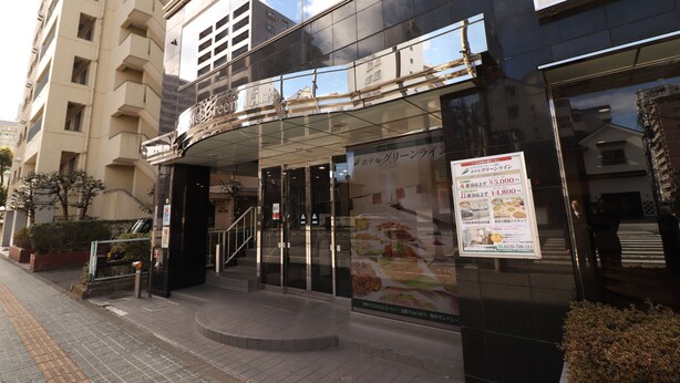 A hotel entrance with a glass facade, a staircase, and a signboard advertising room rates. - Hotel Green Line (Sendai)
