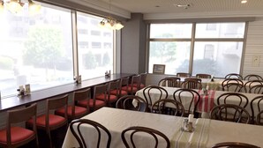 A restaurant with multiple tables and chairs, large windows, and a view of the outside. - Hotel Green Line (Sendai)