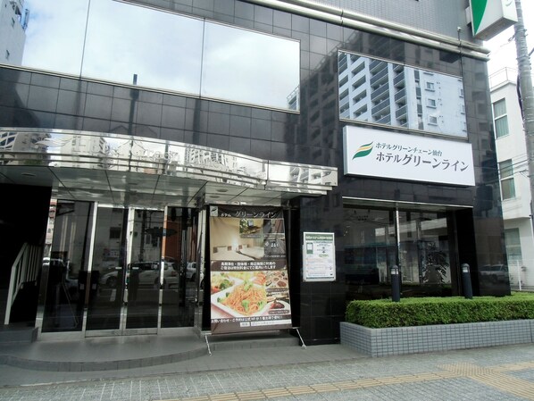 A hotel entrance with a glass door, a signboard, and a small garden area. - Hotel Green Line (Sendai)