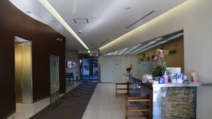 Un vestíbulo de hotel moderno con una recepción, un separador de vidrio y una escalera que sube a otro piso.