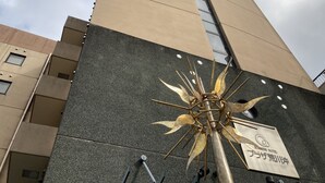 Un edificio con cartel anunciando un hotel de negocios, una estructura alta de diseño moderno y una escultura decorativa de metal.