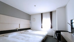 Habitación de hotel con dos camas, un escritorio, una silla, un televisor y una ventana con cortinas.
