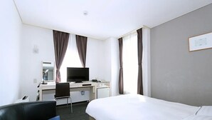 Habitación de hotel con cama, escritorio, computadora, silla y televisor.