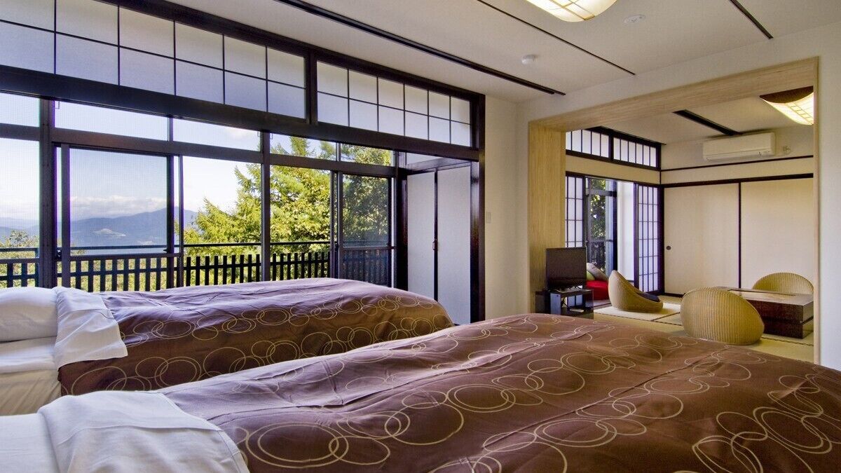 A hotel room with two beds, a desk, and a view of mountains.