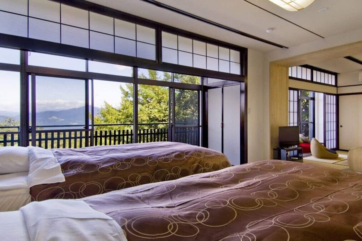 Ein Hotelzimmer mit zwei Betten, einem Schreibtisch und Bergblick.