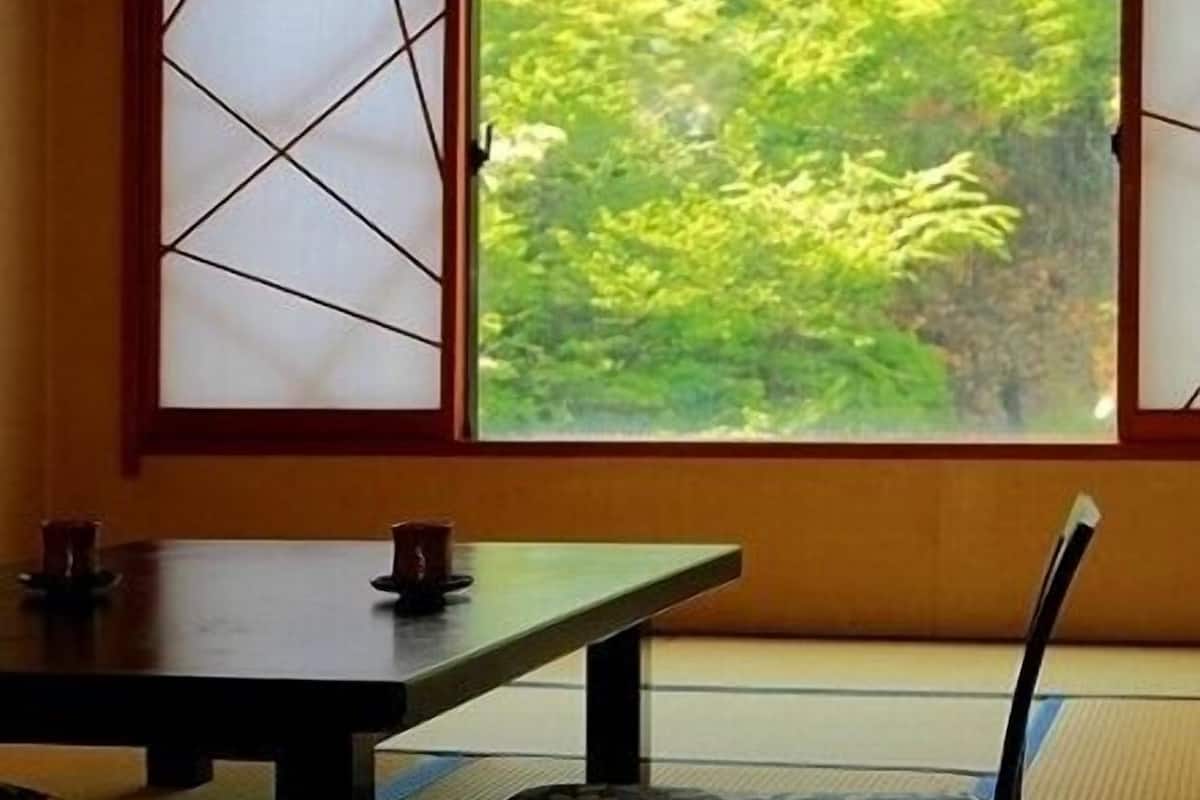 Ein traditioneller japanischer Raum mit Tatami-Boden, einem niedrigen Tisch und einer gepolsterten Sitzbank.