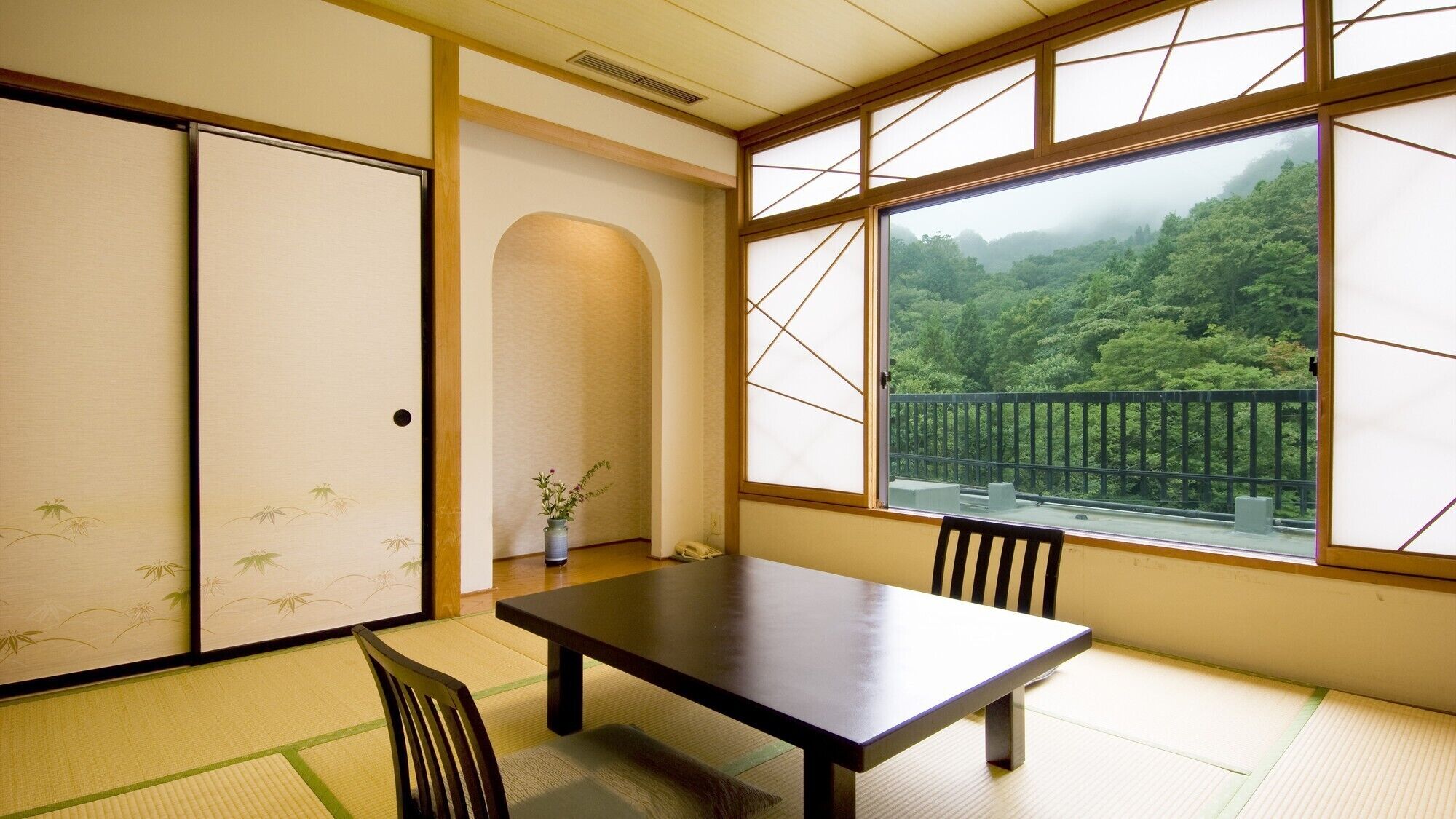A traditional Japanese room with tatami flooring, a low table, and sliding doors.