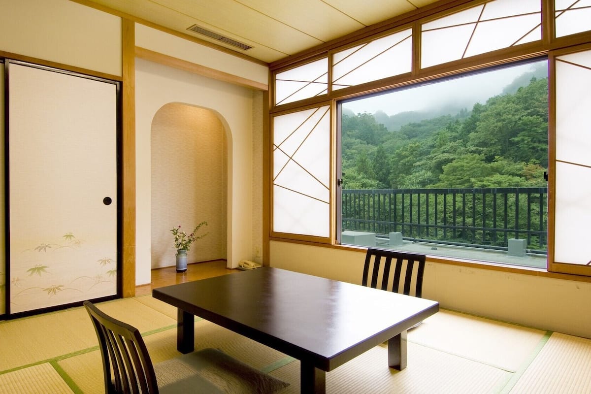 Ein traditioneller japanischer Raum mit Tatami-Boden, einem niedrigen Tisch und gleitenden Türen.