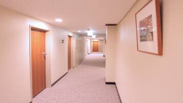 A hotel hallway with carpeted floors, wooden doors, and a framed picture on the wall.