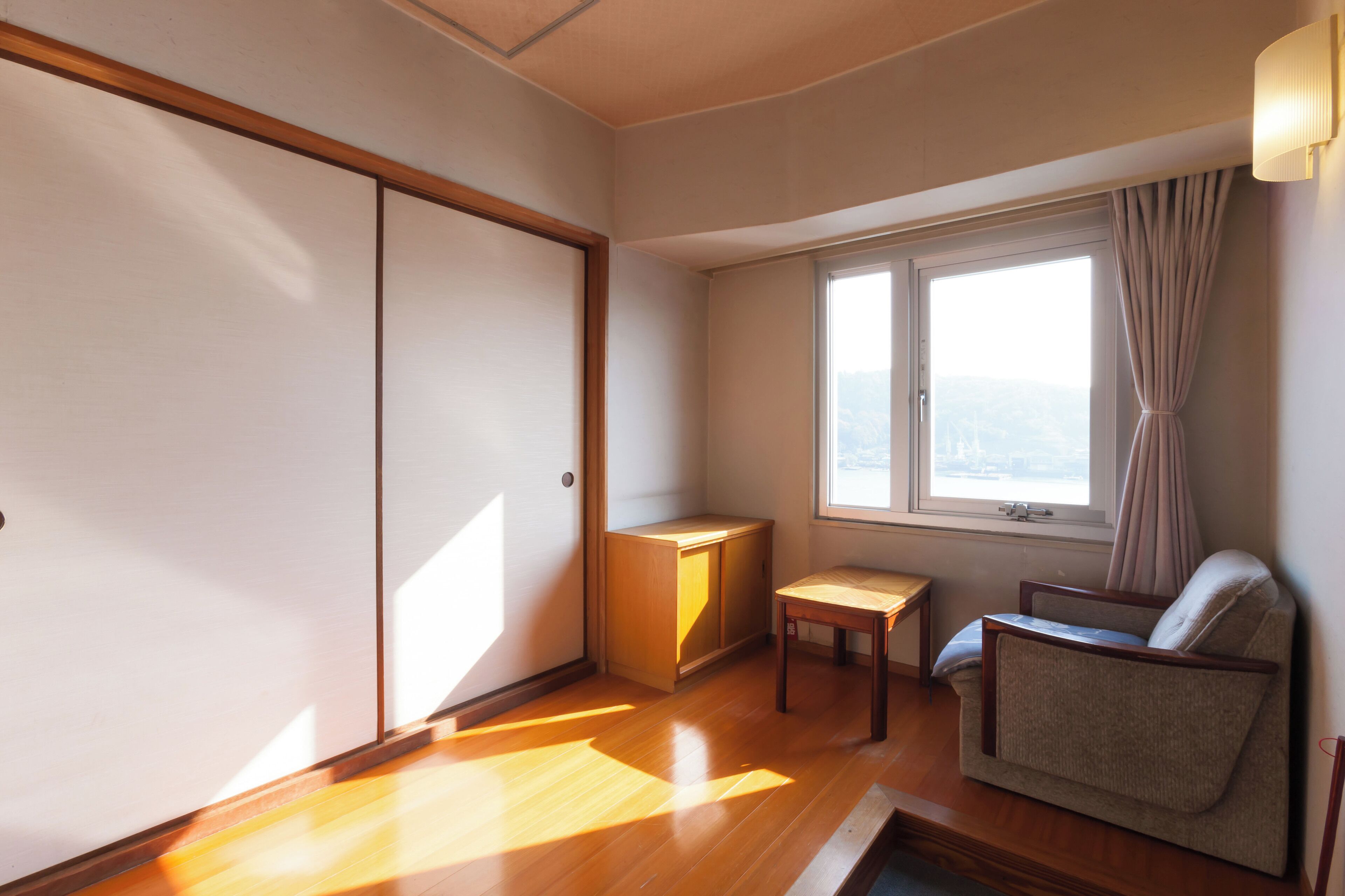 A room with a sliding door, a small table, a sofa, and a window with curtains.
