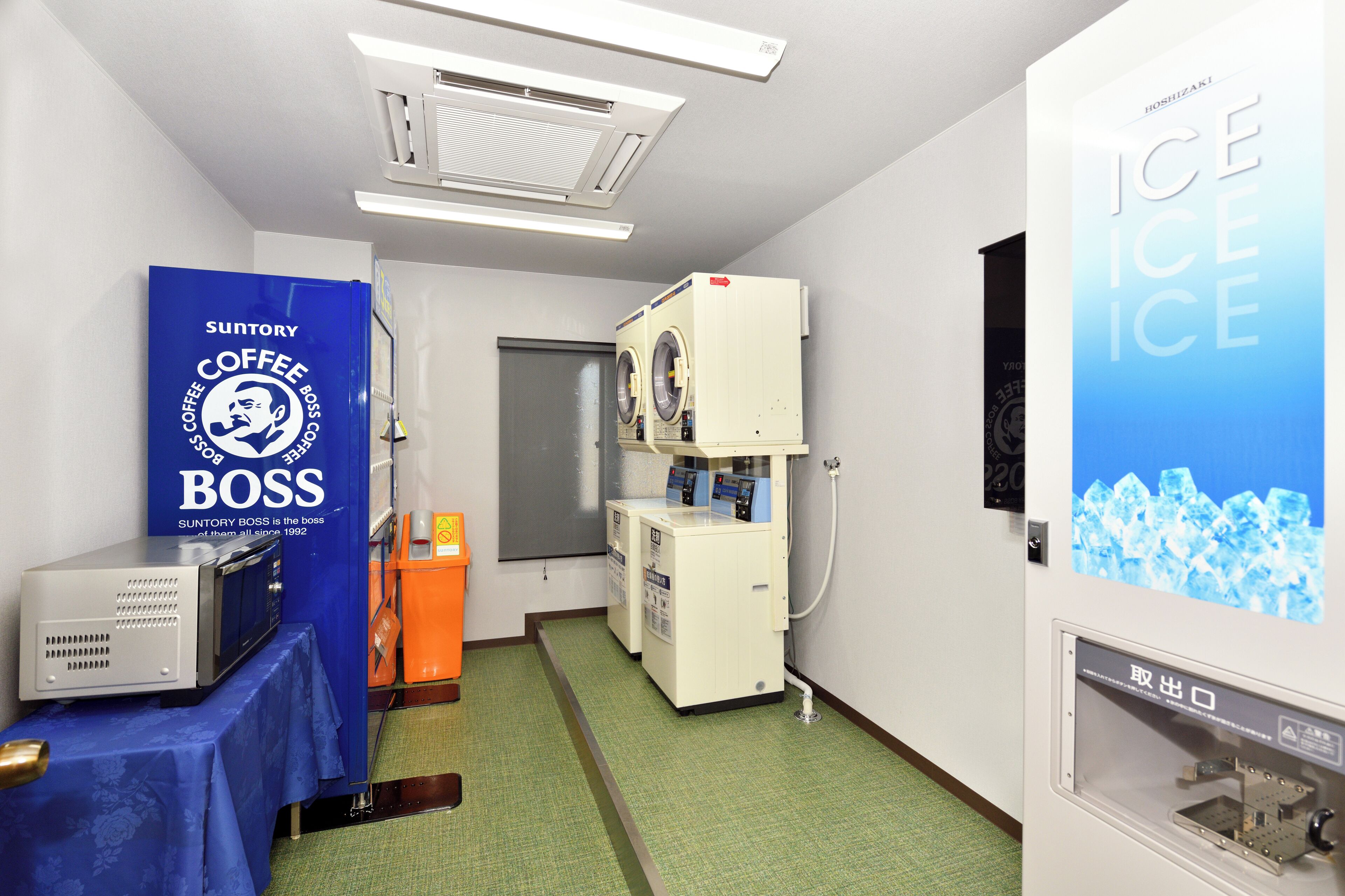 A room with a washing machine, a coffee machine, and a refrigerator.
