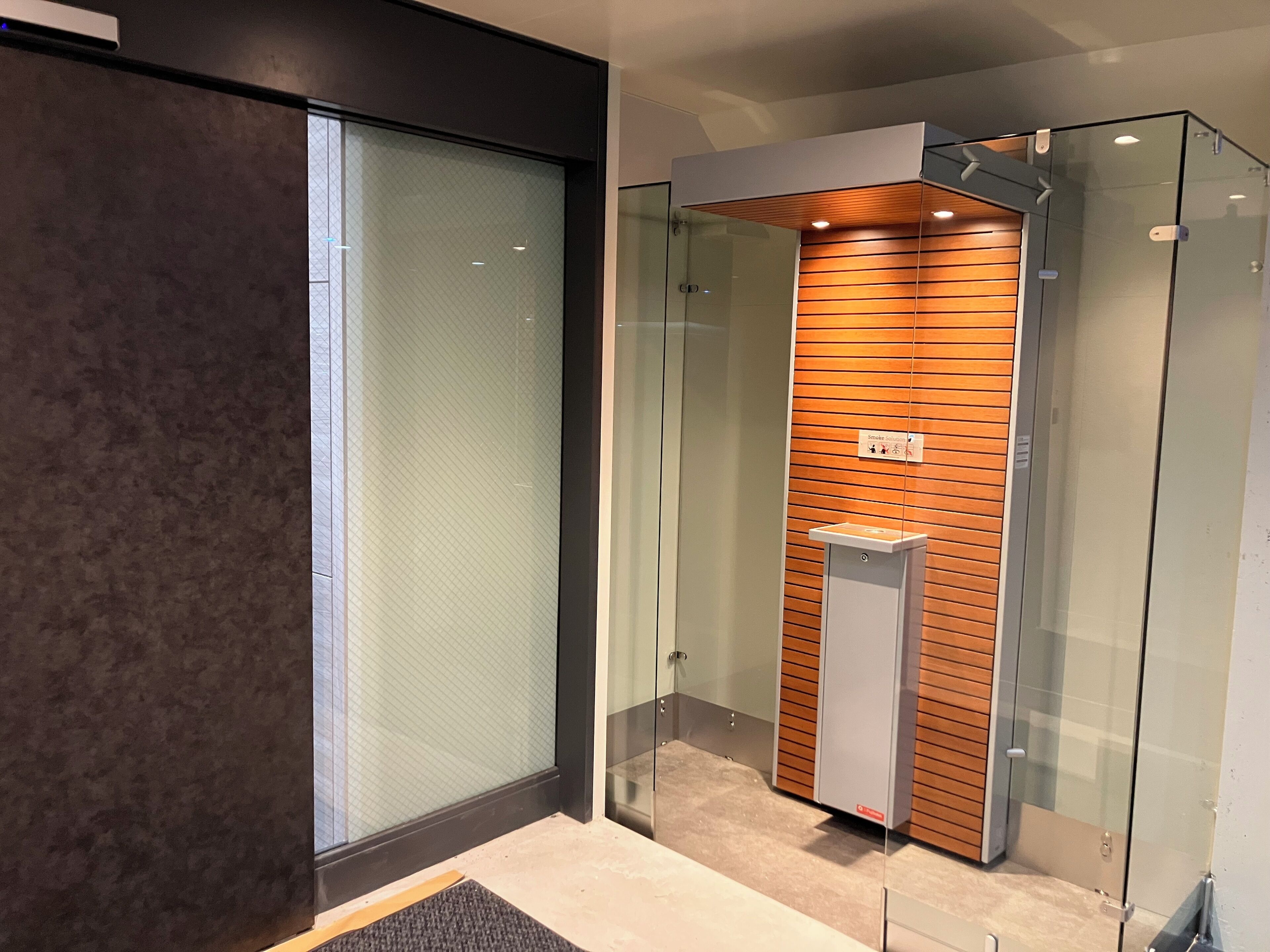 A modern elevator with glass doors and a wooden panel interior.