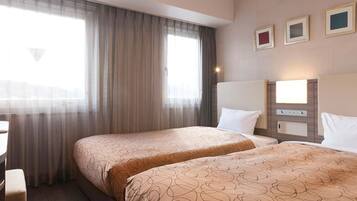 Habitación de hotel con dos camas, un escritorio, un espejo y una ventana con cortinas.