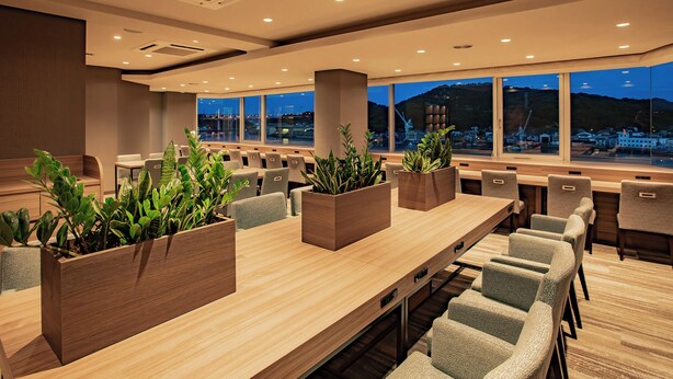 A conference room with a long table, multiple chairs, and potted plants. - Onomichi Royal Hotel (Onomichi)