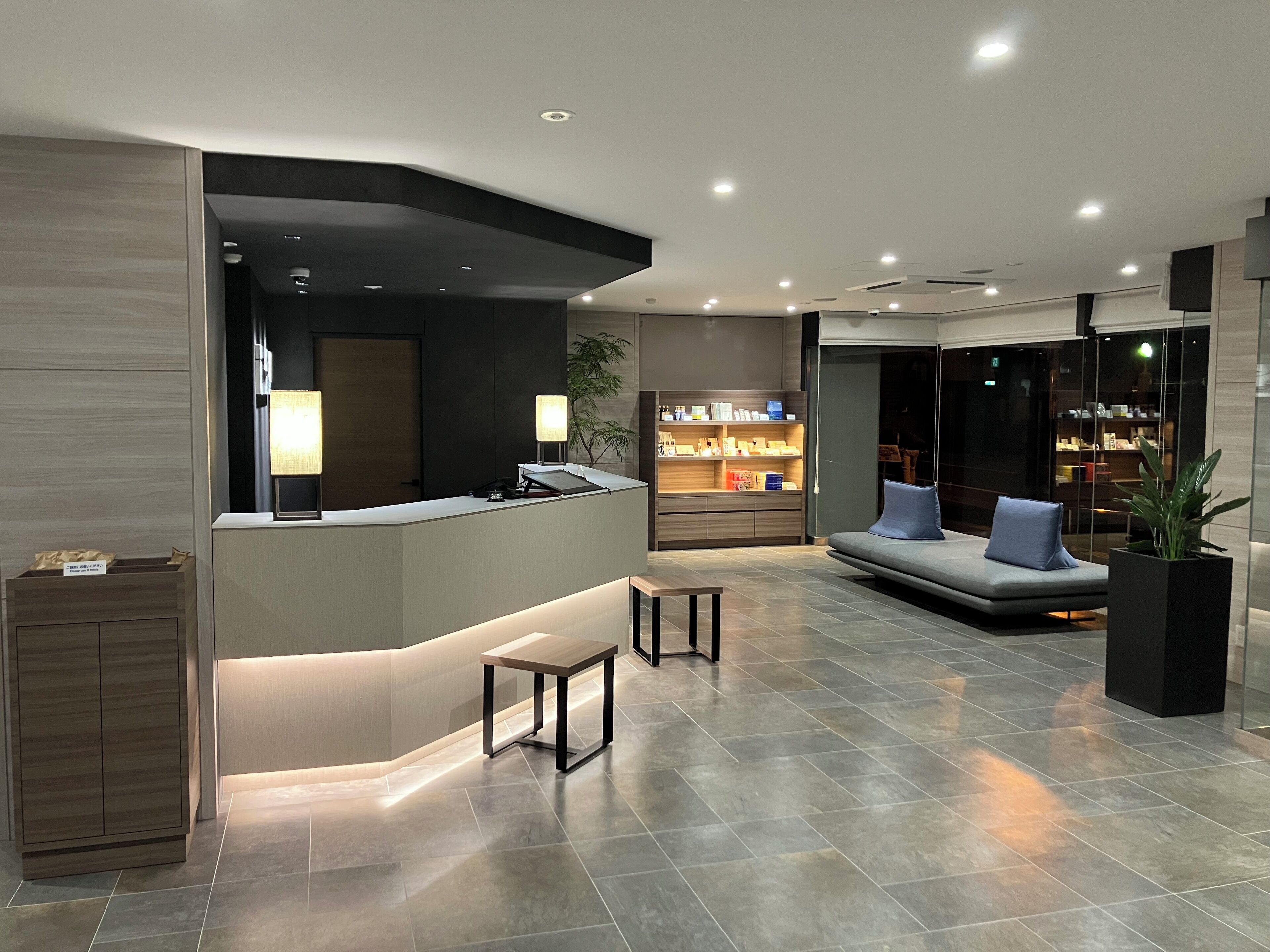 A modern lobby with a reception desk, seating area, and a display of products.