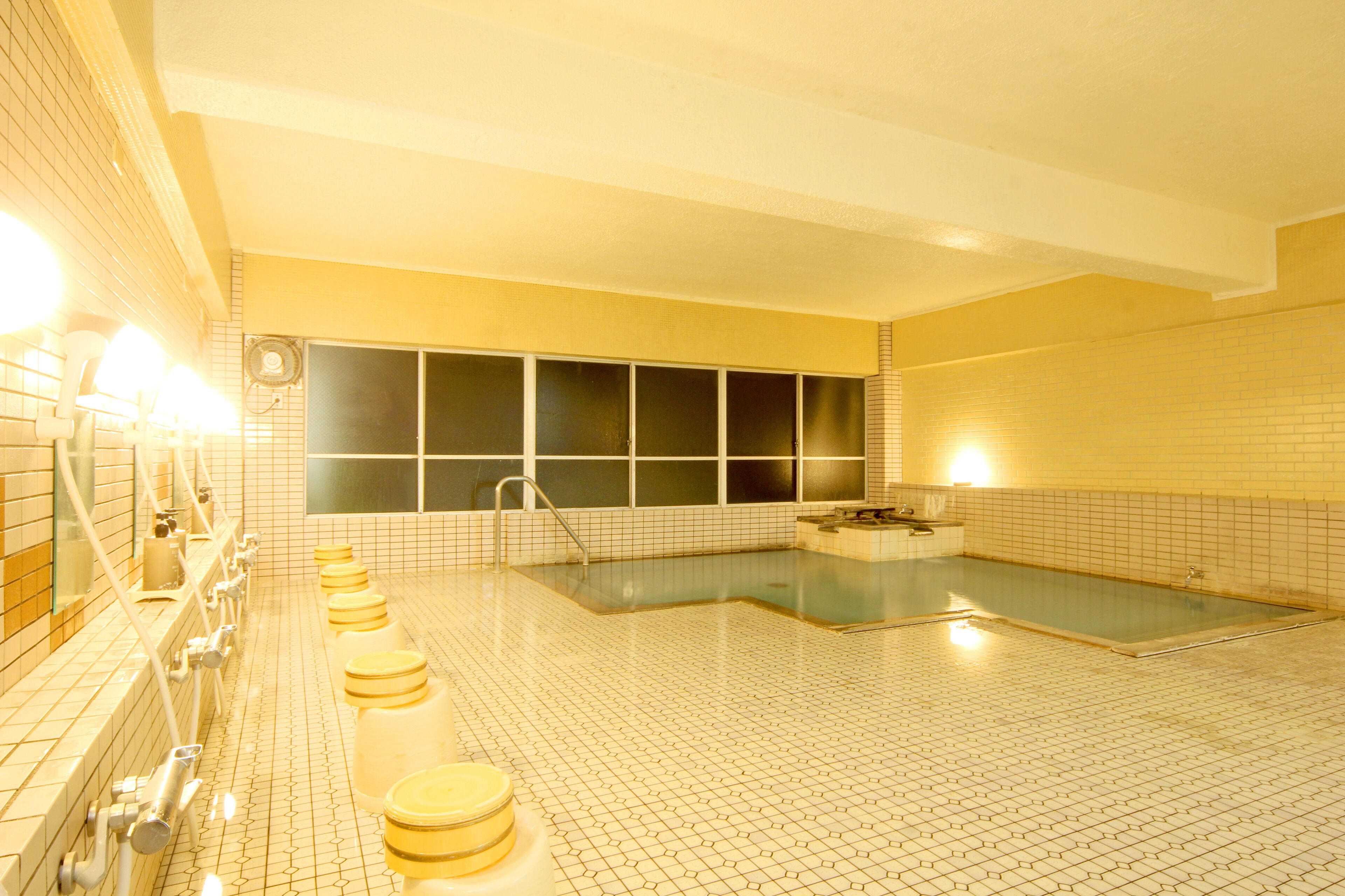 A large indoor swimming pool with multiple lanes, a changing room area with benches, and a sauna area.