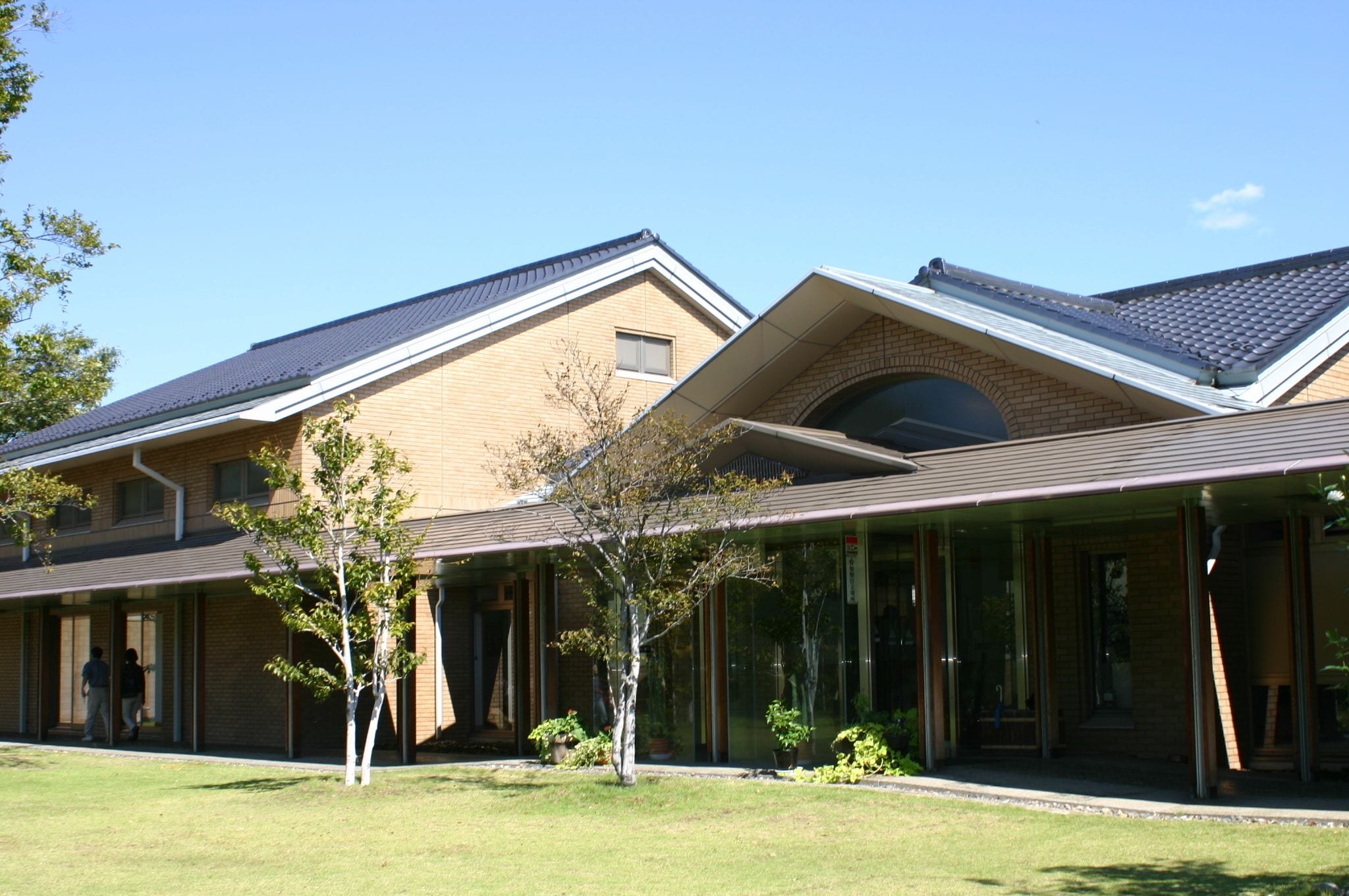 A modern building with a brick facade, large windows, and a covered entrance area.